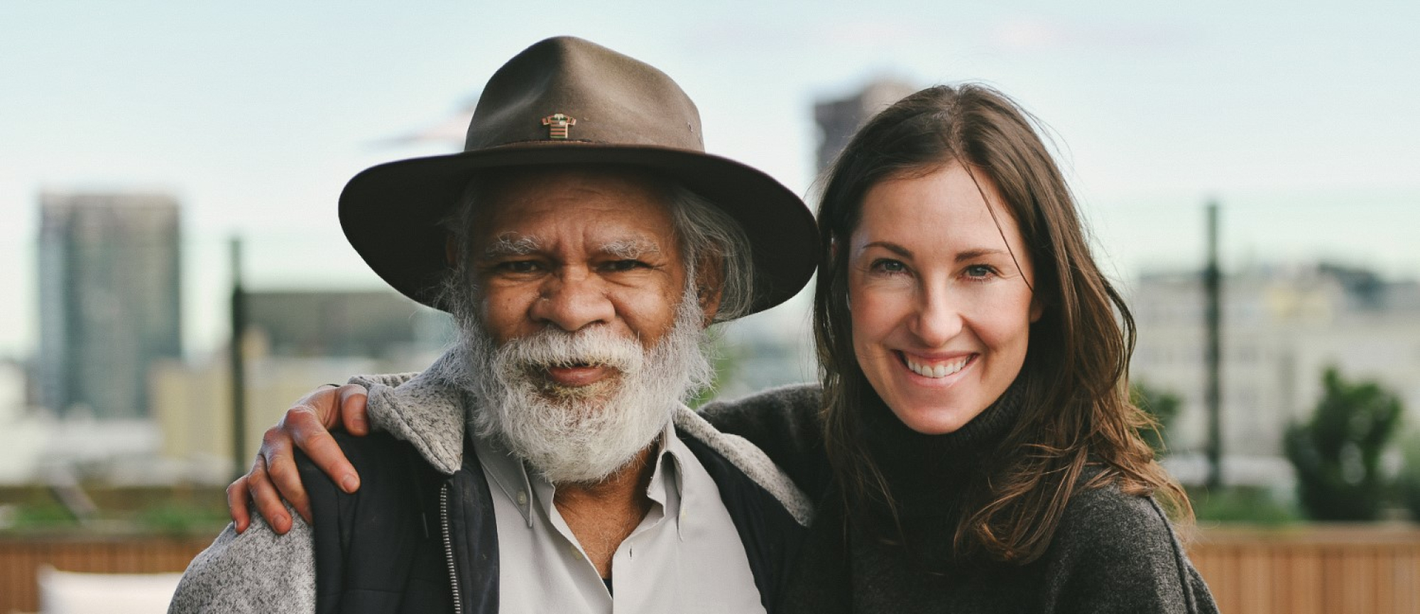 Two indigenous people looking at smiling at camera.