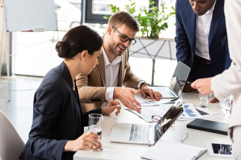 Office workers at a desk with laptops and papers discussing working capital solutions