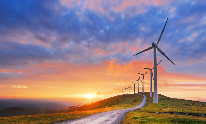 Wind turbines with a sunset in the background.