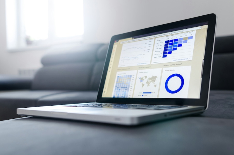 Close up of a laptop sitting on a grey couch with the screen open and a financial statement on the screen