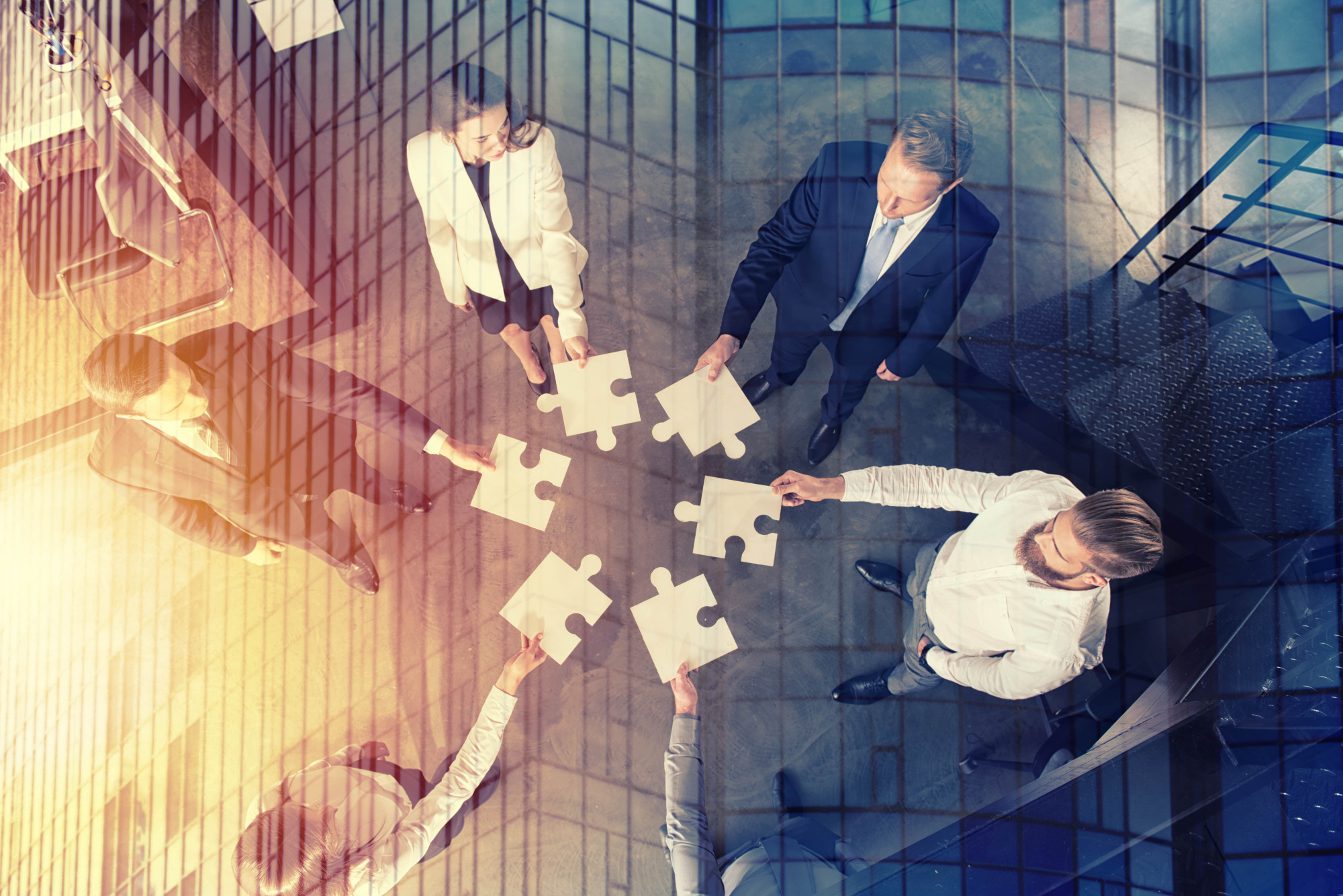 Birds eye view of table with business people and puzzle pieces coming together.