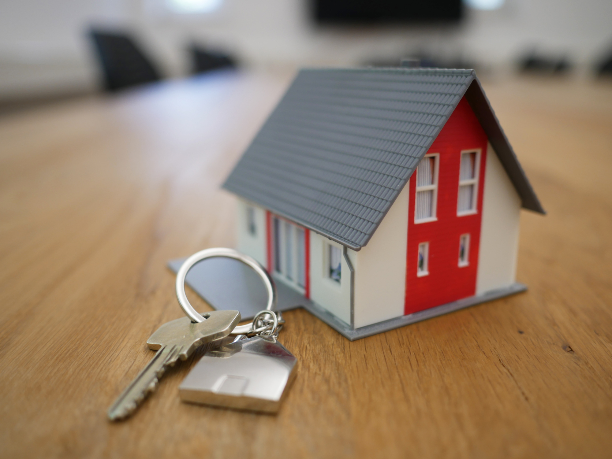Keys to a home and toy house on a table.