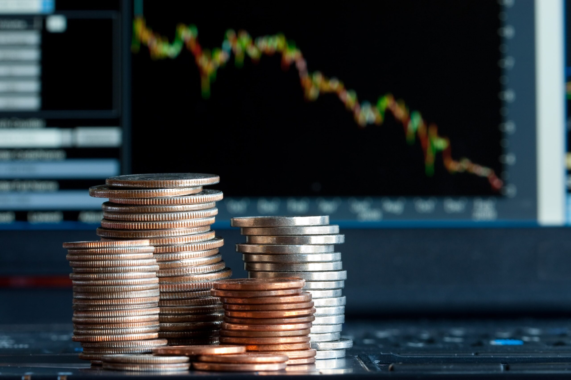 Stacks of coins and a down trend chart as the background.