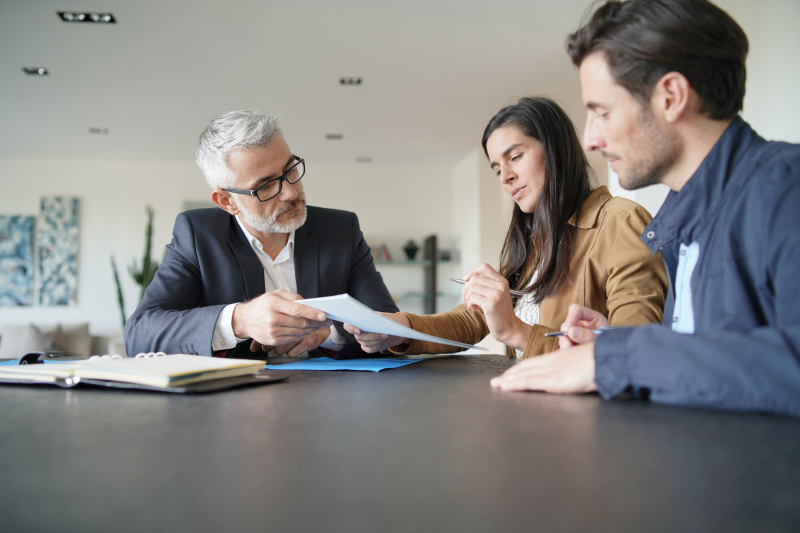 Couple signing contract with real-estate agent in contemporary house.