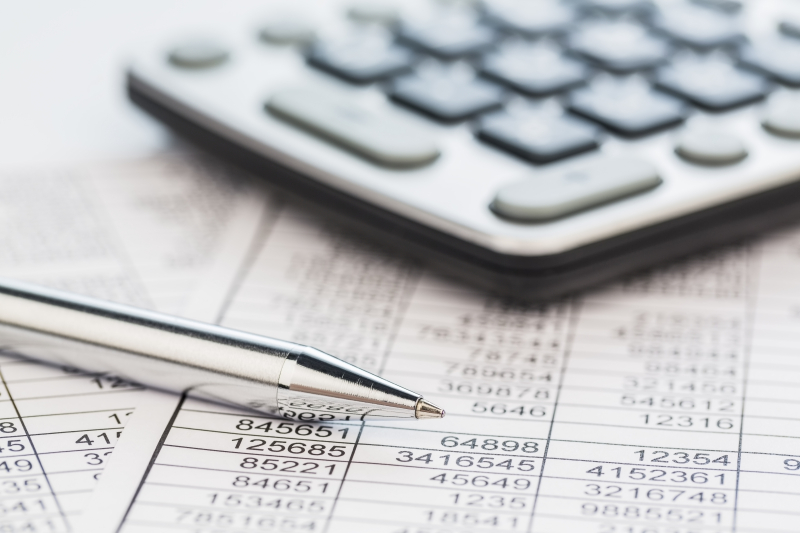 A calculator is on a balance sheet numbers are statistics. photo icon for sales, profit and cost.