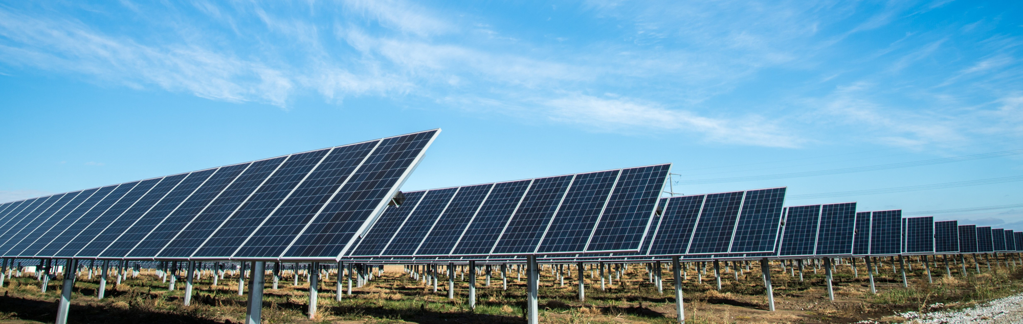 Solar panel farm with blue sky in the background.