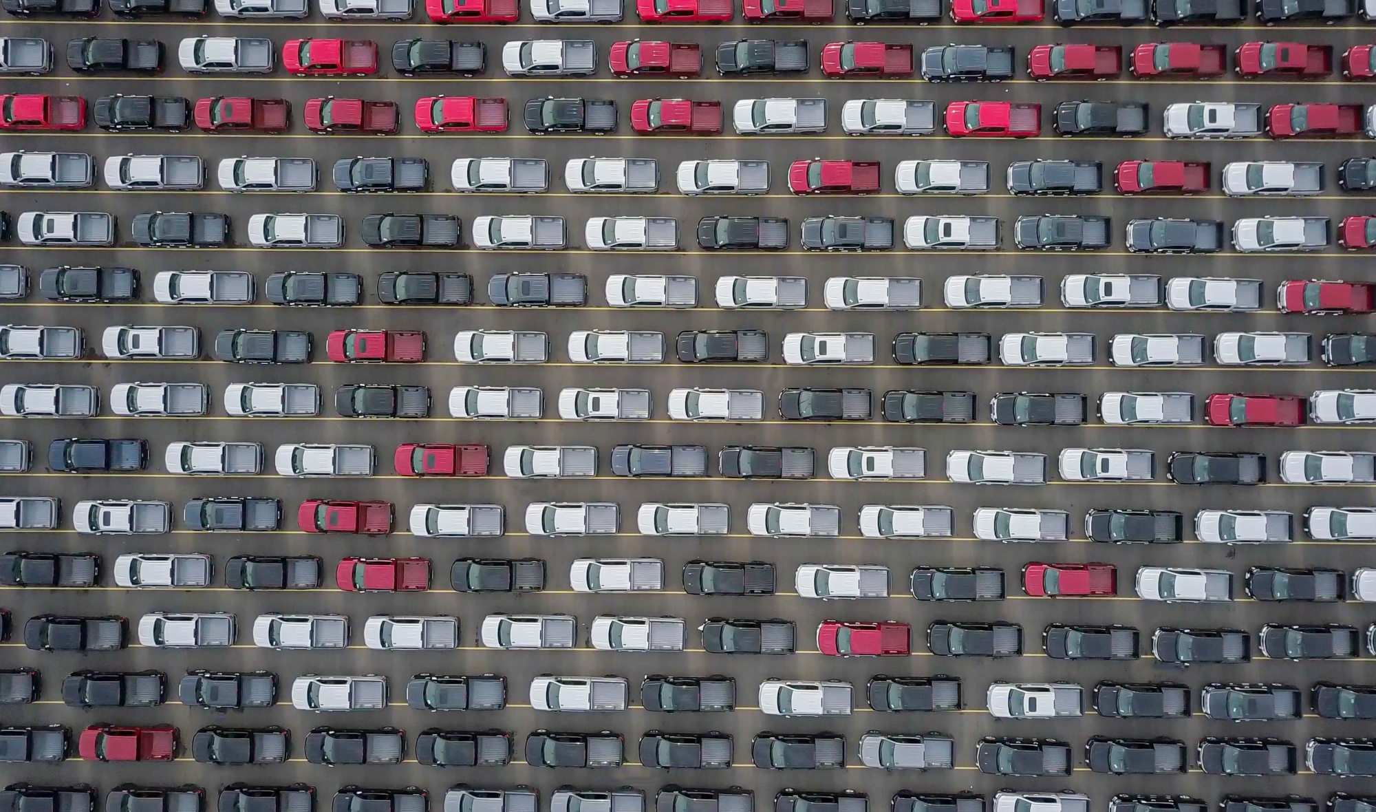 aerial view of a fleet of cars parked in rows on road