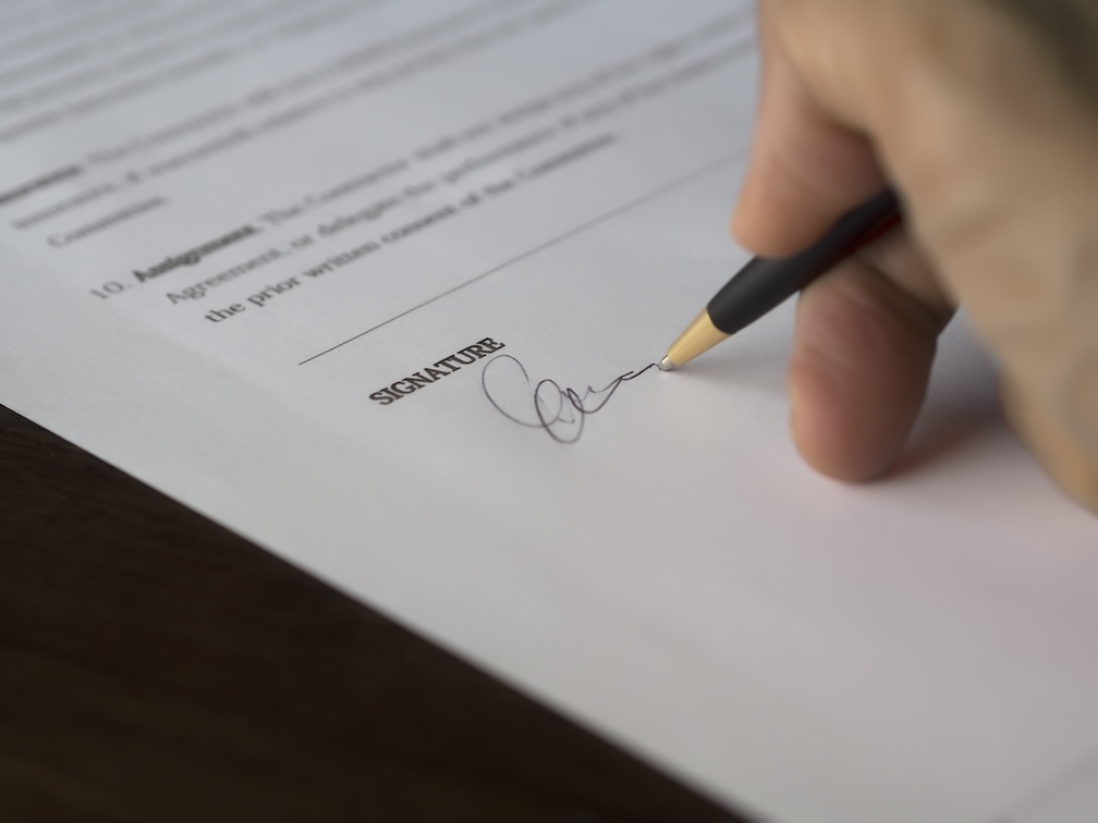 The 10 Commandments of Terms of Trade: Protecting Your Business 2 Close-up of a hand signing a contract with a pen on a business document.